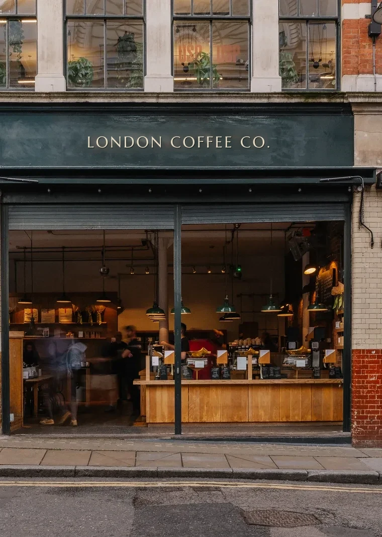 The London Coffee Co. shopfront on a Borough street corner, doors open onto a warm wooden counter
